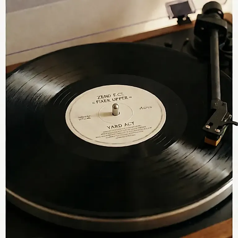 Un vinyle noir de « Fixer Upper » tourne sur une platine, étiquette centrale et sillons visibles, lumière chaude.